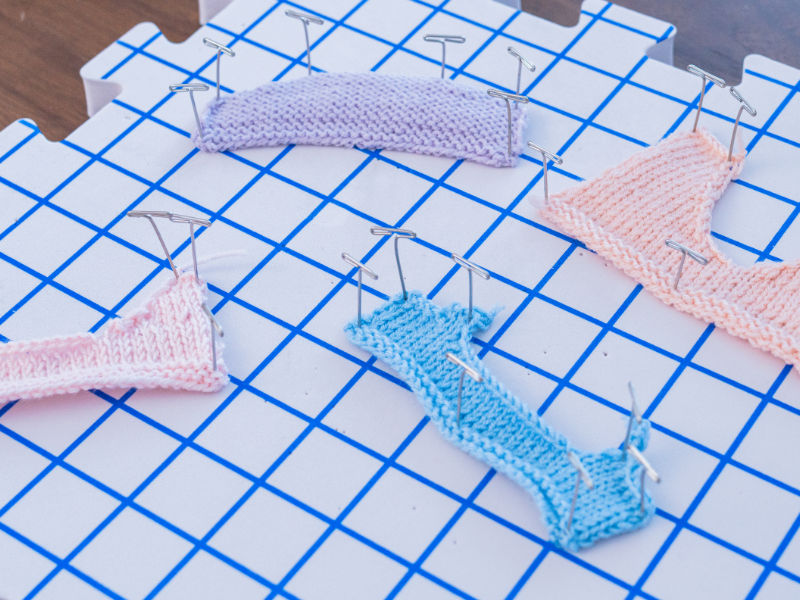 Mini cols au tricot sur un tapis de blocage