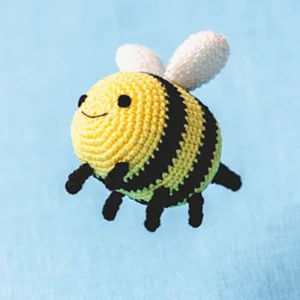 Une jolie abeille jaune et noire crochetée avec des ailes blanches et un visage souriant est placée sur un fond bleu clair, parfaite pour ceux qui recherchent des PDF gratuits d’amigurumis en français.