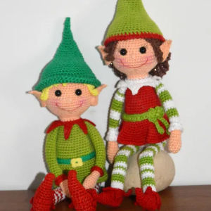 Deux poupées elfes crochetées, coiffées de chapeaux pointus, de bas rayés verts et blancs, de chaussures rouges et de grandes oreilles pointues, sont assises côte à côte. L'une porte des vêtements verts et des cheveux blonds ; l'autre une robe rouge et des cheveux bruns.