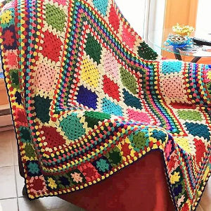 A colorful crocheted blanket is sitting on a chair