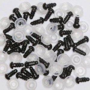 Une collection de petits yeux de sécurité en plastique noir et de rondelles en plastique transparent dispersés sur une surface blanche, couramment utilisés pour fabriquer des animaux en peluche et des poupées.