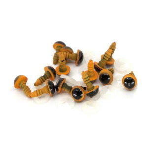 Un groupe de petits yeux de sécurité en plastique avec des bases orange et des pupilles noires, couramment utilisés pour fabriquer des animaux en peluche ou des poupées, dispersés sur une surface blanche.
