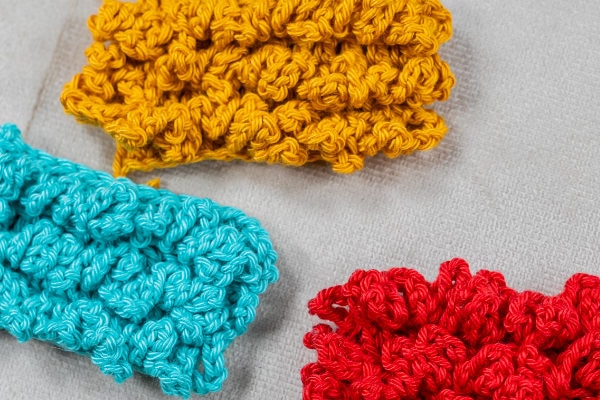 Un groupe de pièces colorées au crochet, magnifiquement réalisées en utilisant la technique complexe du point d'astrakan au crochet.