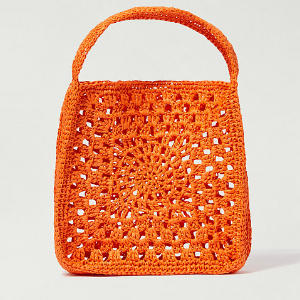 Un petit sac en crochet orange de forme carrée avec une seule anse et un motif ajouré circulaire et carré complexe sur le devant.