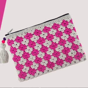 Une pochette au crochet à fermeture éclair avec un motif à carreaux roses et blancs, avec un petit pompon en perles roses, violettes et blanches attaché à la fermeture éclair - une charmante pochette au crochet avec explication gratuite pour vos accessoires.