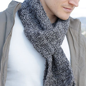 Une personne portant un écharpe homme au crochet, une veste gris clair et une chemise blanche. Seule la partie inférieure du visage et le haut du corps sont visibles.