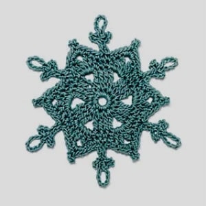 Un flocon de neige au crochet de couleur sarcelle avec six pointes et des boucles complexes, sur un fond gris clair uni.