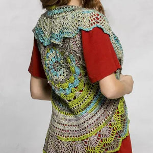 Une personne portant une chemise rouge et un gilet crocheté coloré avec des motifs circulaires et festonnés dans des tons bleus, verts et beiges, vu de dos.