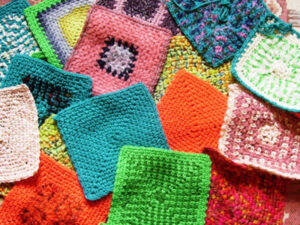 Une variété de carrés de grand-mère colorés est étalée, présentant différents motifs et des couleurs vives comme le rose, le vert, le bleu, l'orange et le violet - une inspiration parfaite si vous cherchez un modèle de carré au crochet gratuit.