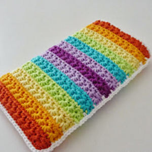 Une pièce rectangulaire au crochet, ornée de rayures texturées aux couleurs de l'arc-en-ciel — rouge, orange, jaune, vert, bleu et violet — et soulignée d'une bordure blanche, présentée sur un fond blanc uni.