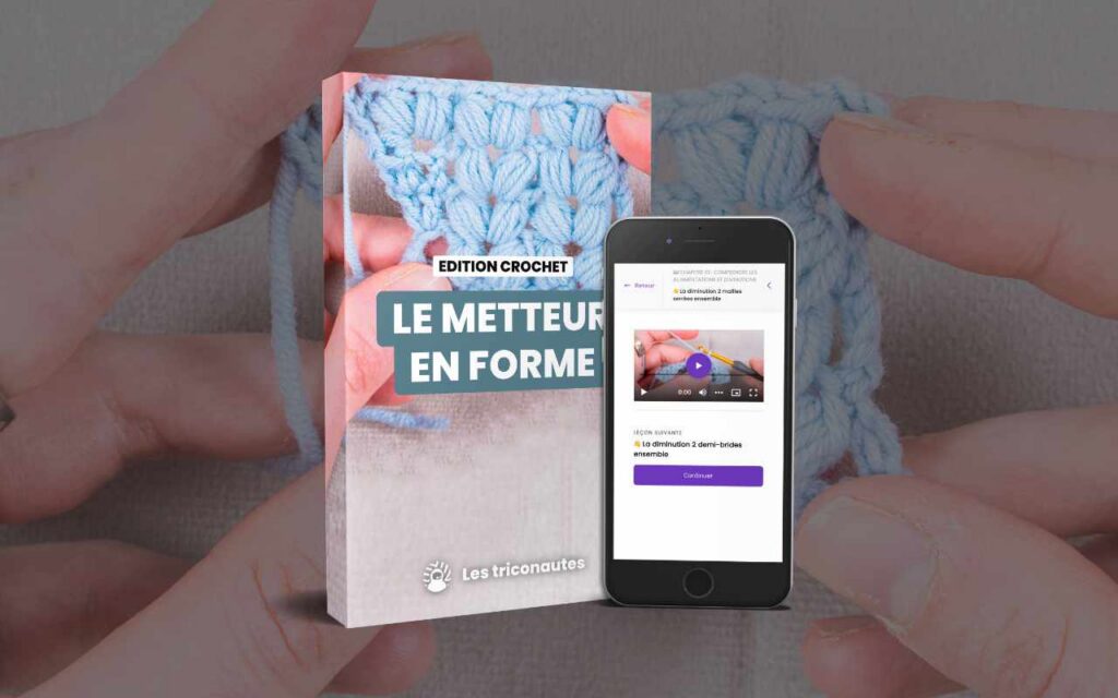 On voit, devant des mains occupées à travailler avec de la laine bleue, un guide de crochet et un smartphone sur lequel est diffusée une vidéo tutorielle de crochet.