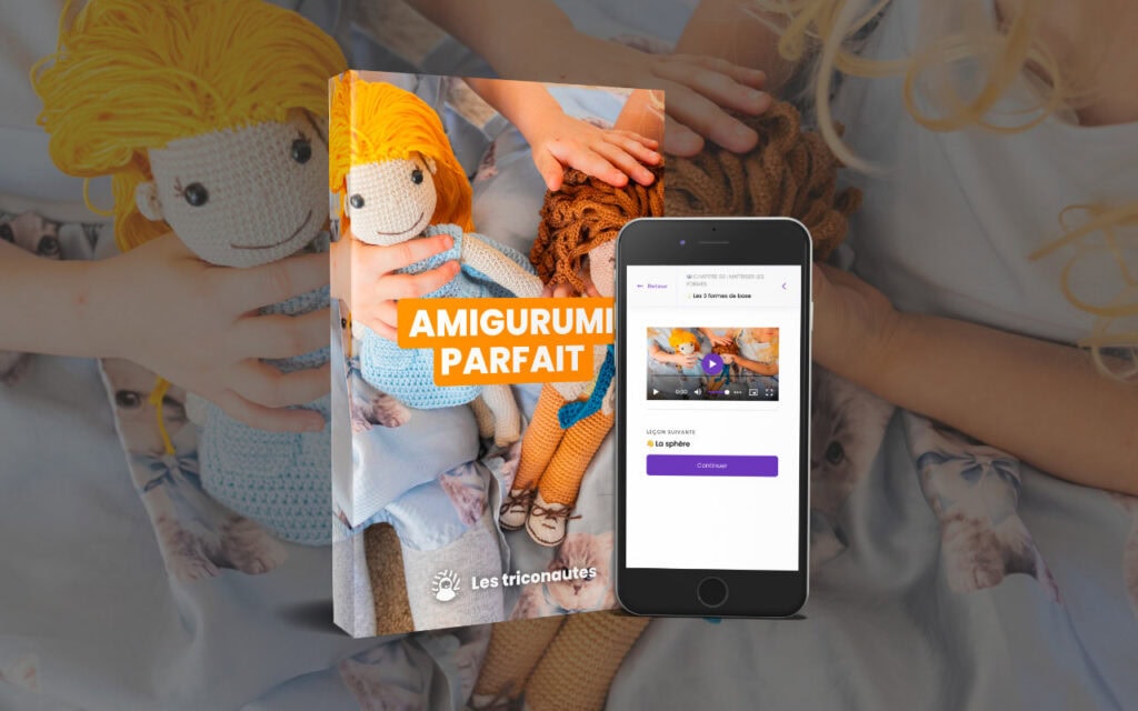 Un livre intitulé « Amigurumi Parfait », dont la couverture représente des poupées au crochet, à côté d'un smartphone affichant une application sur le même thème, tenu par une personne vêtue d'une robe bleue ornée de poupées au crochet.
