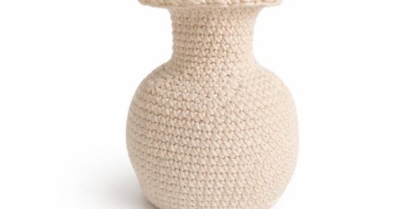 Vase rond de couleur crème, au bord large et évasé, cet objet au crochet est réalisé à partir d'un fil crocheté serré et présenté sur un fond blanc.